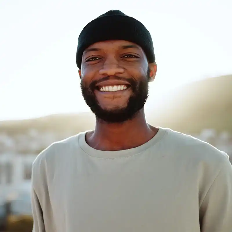 a man in a black beanie and white shirt smiles at the camera