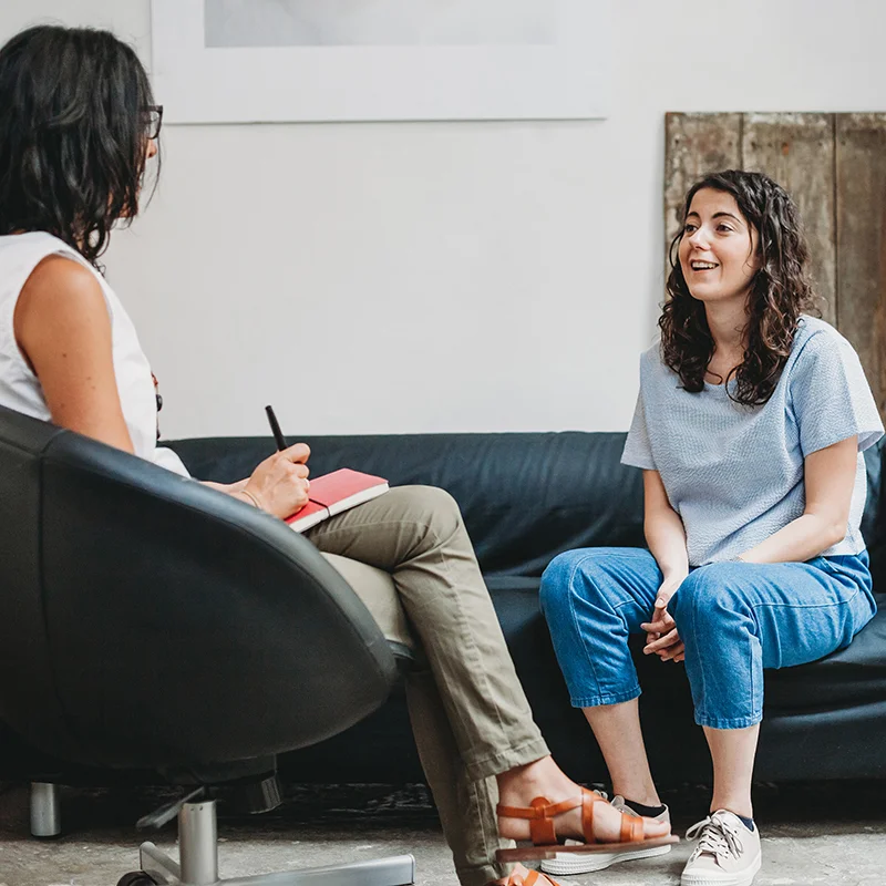 A clinician and a client talking in a therapy session