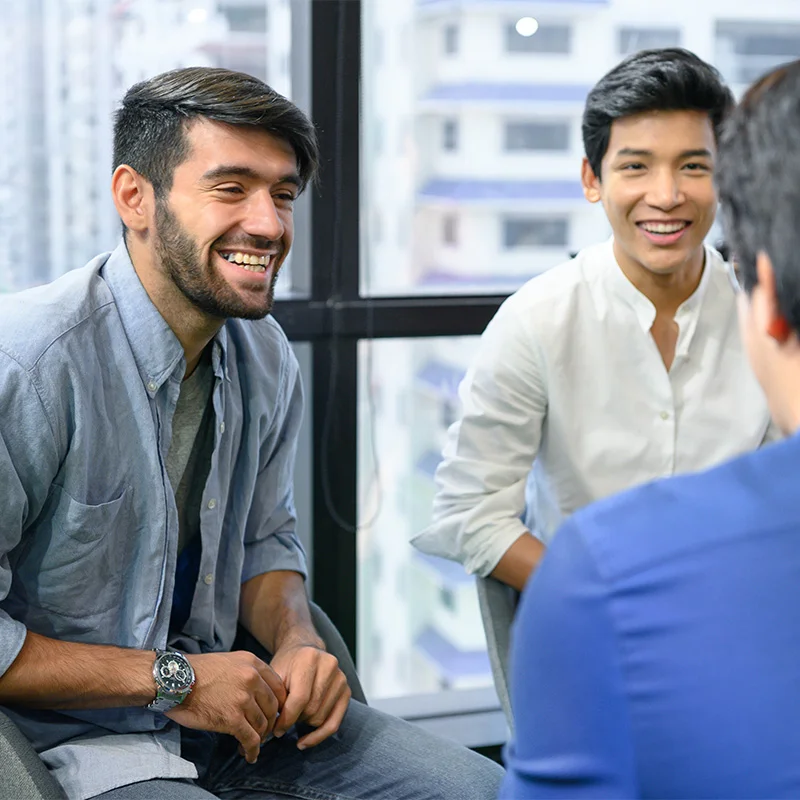 a man speaks to a specialist about paying for addiction treatment with a friend present for support