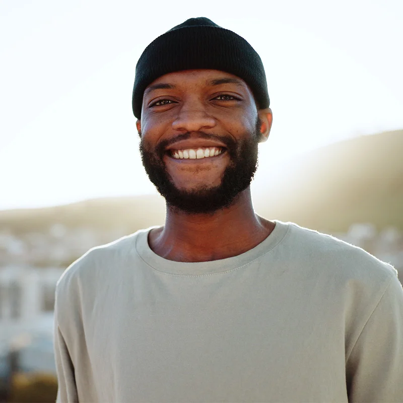 a man in a black beanie and white shirt smiles at the camera