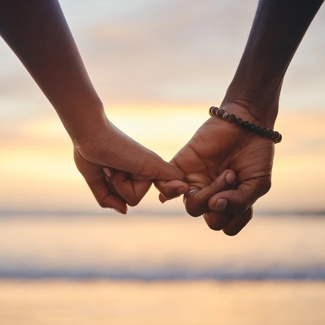 two friends make a pinky promise on the beach at sunset