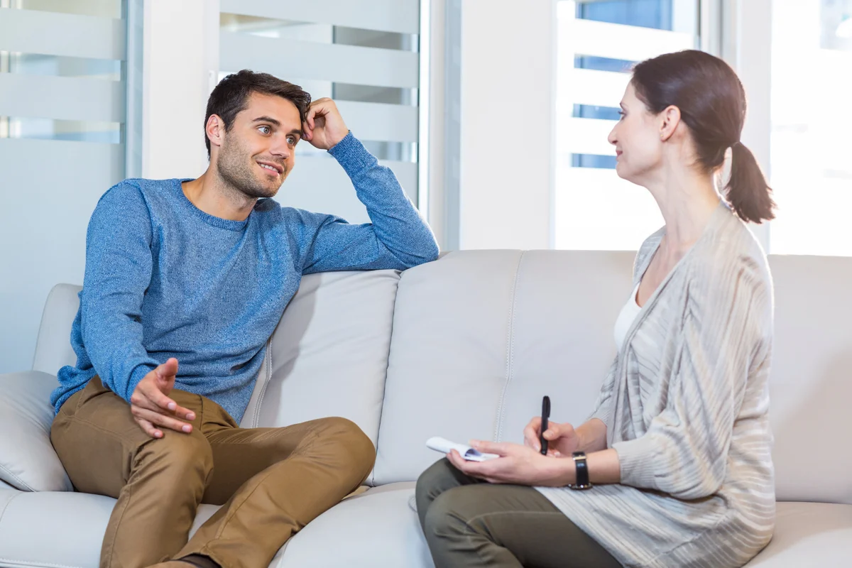 Man smiling talking to woman on couch